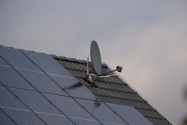 Ein an einer Ziegelwand neben einem Metallmast befestigtes elektrisches Metallrohr.