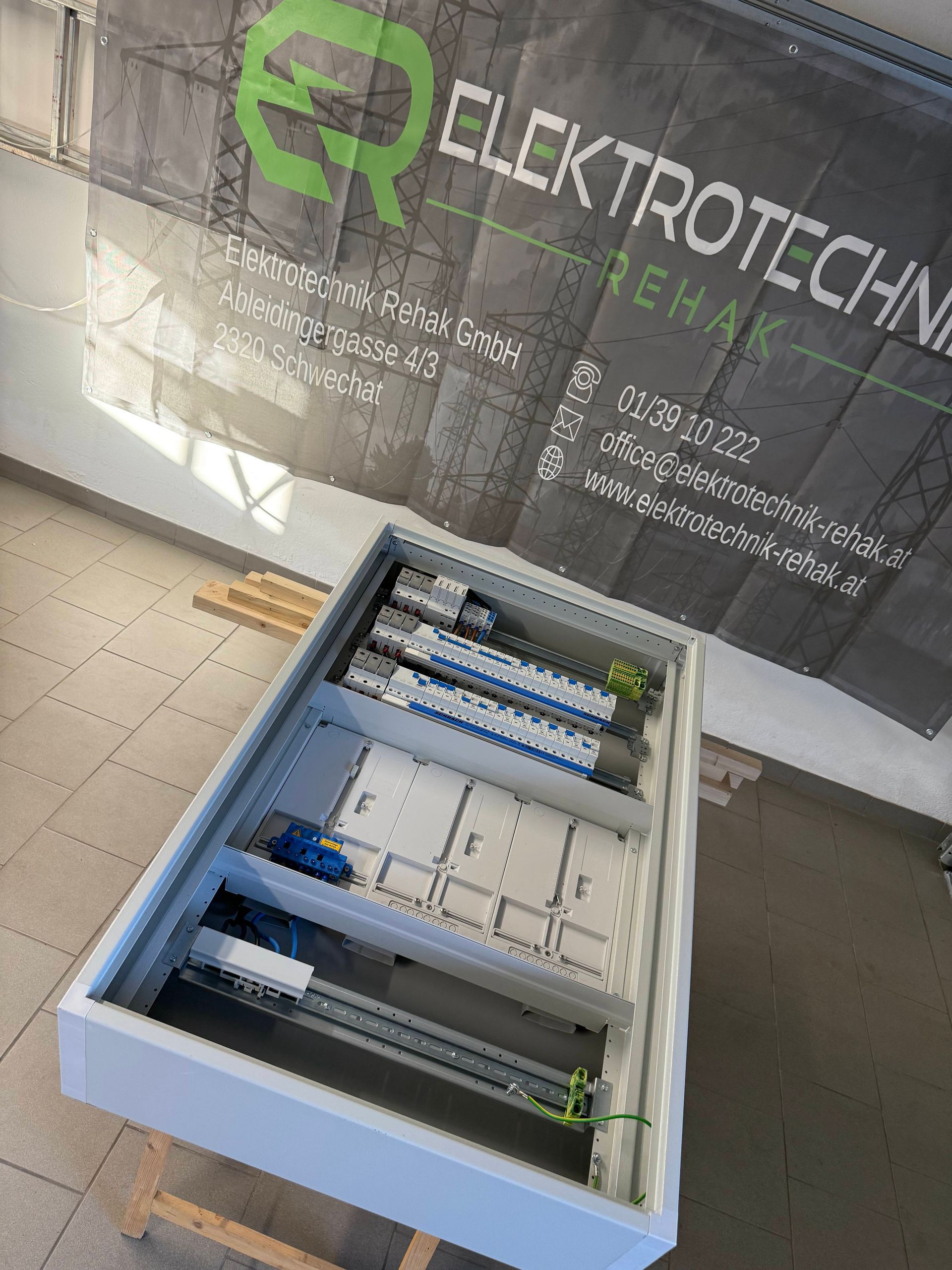 Offener elektrischer Schaltschrank mit blauer und grüner Verkabelung unter einem ElektroTech-Banner
