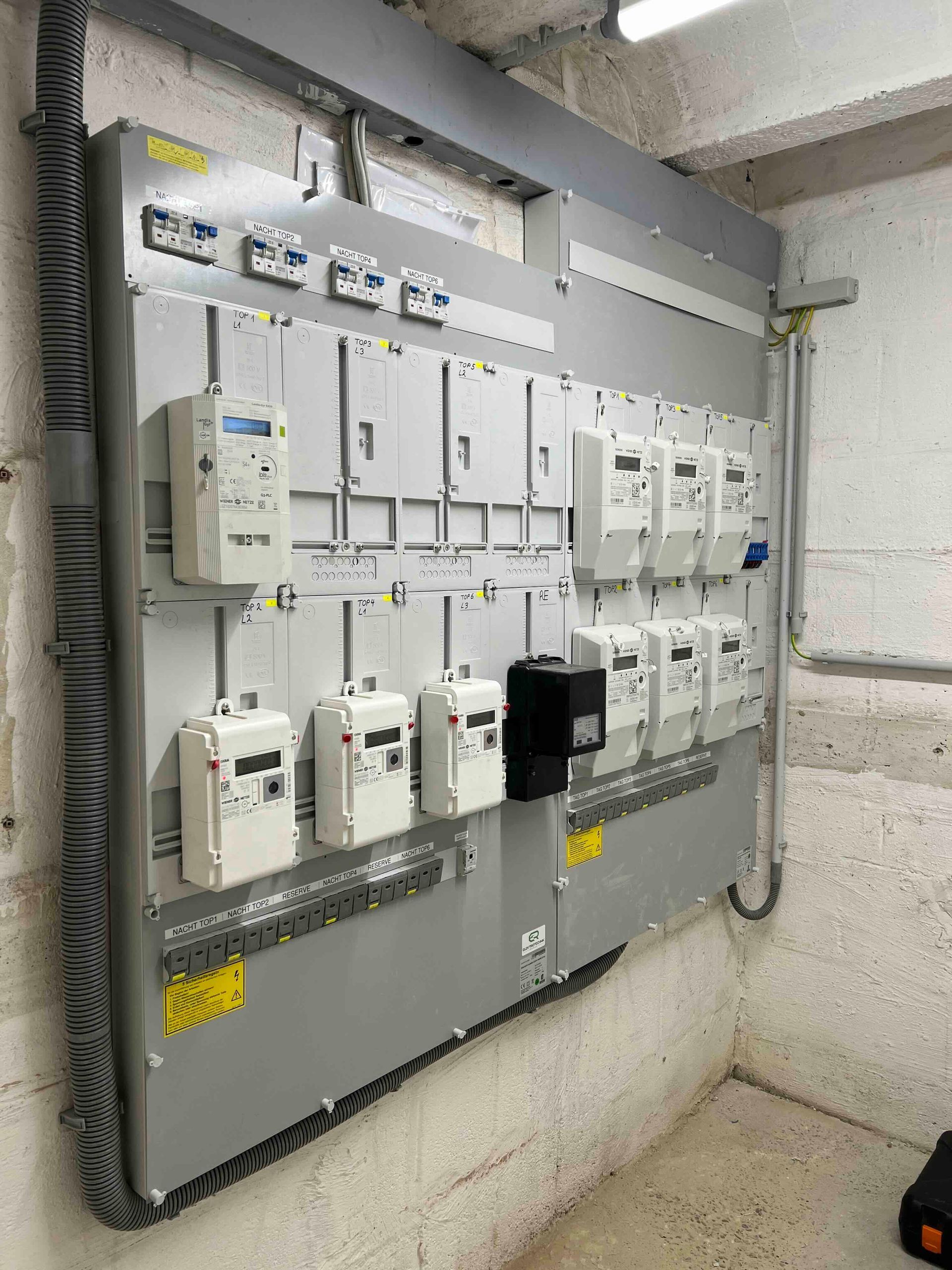 Elektrischer Sicherungskasten und Stromzähler sind in einem Hauswirtschaftsraum an einer Wand montiert.
