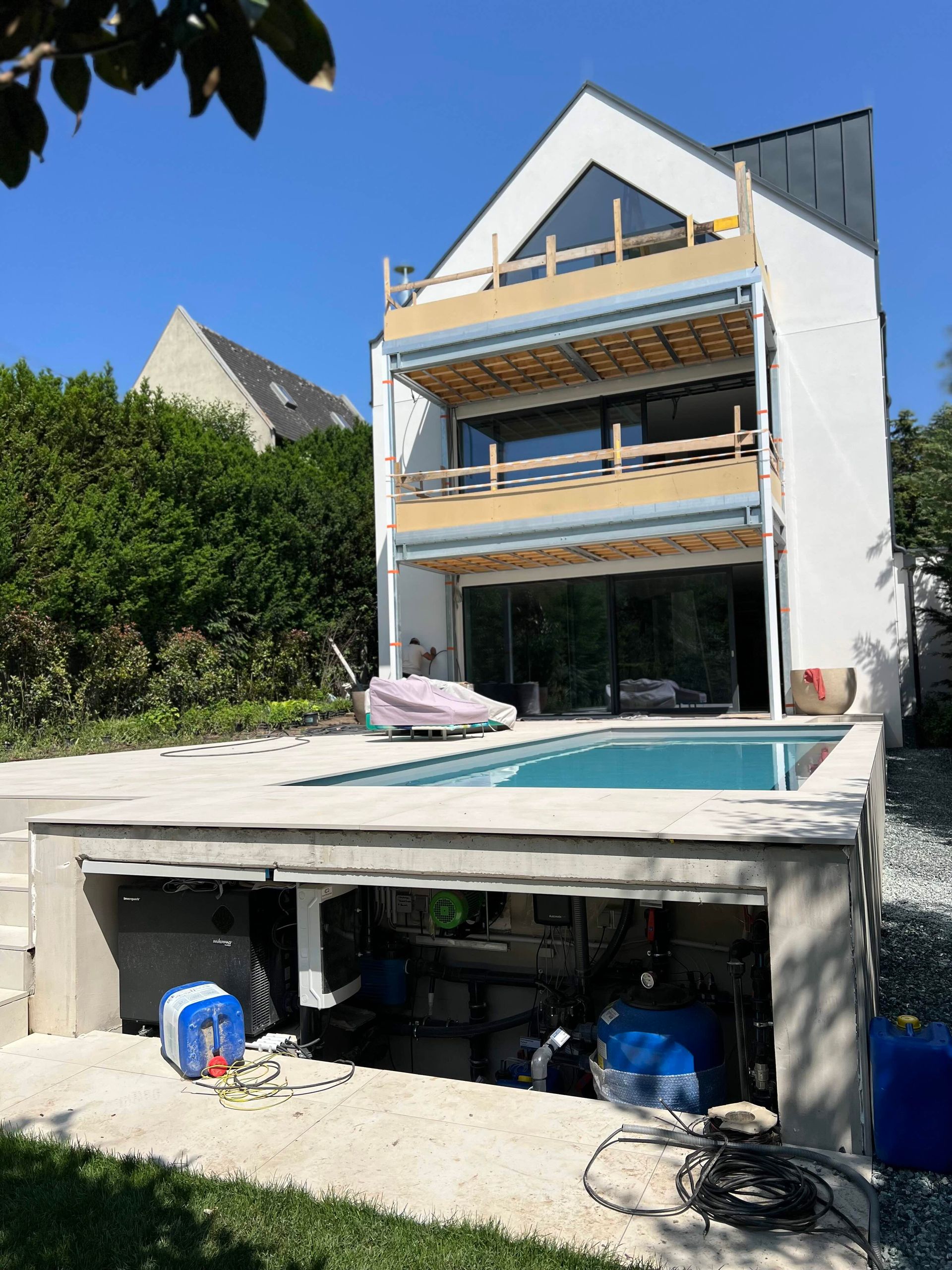 Modernes Haus mit Pool und Betoncarport vor strahlend blauem Himmel.