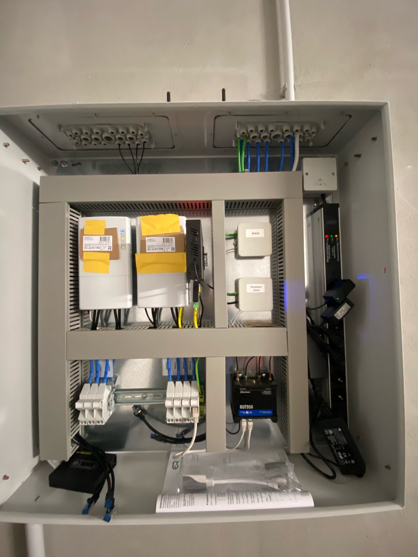 Offener elektrischer Schaltschrank mit Verkabelung, Sicherungen und Schaltkreismodulen in einem grauen Metallgehäuse