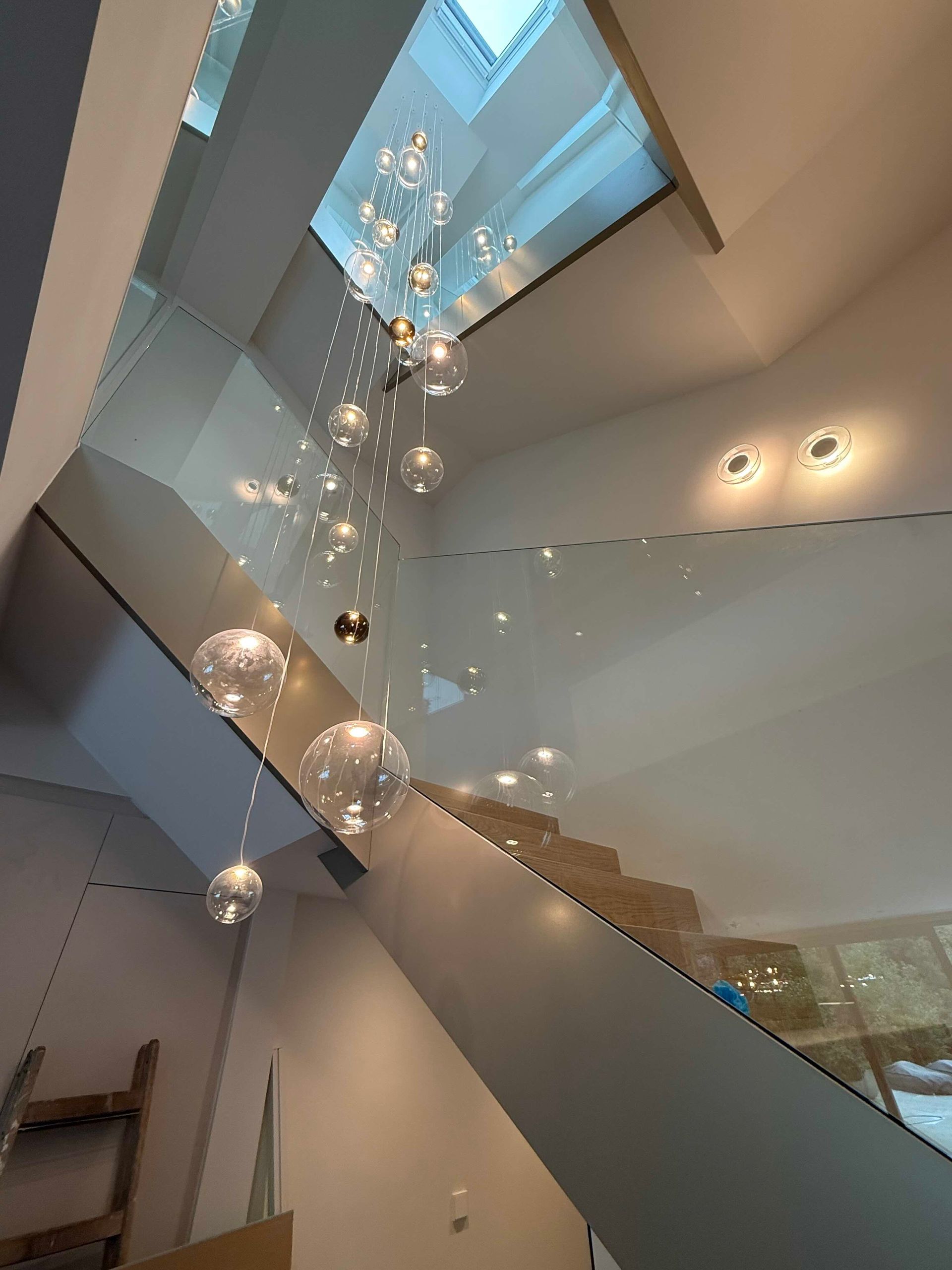 Modernes Treppenhaus mit Oberlichtern und hängenden Kronleuchtern in einem hellen Atrium