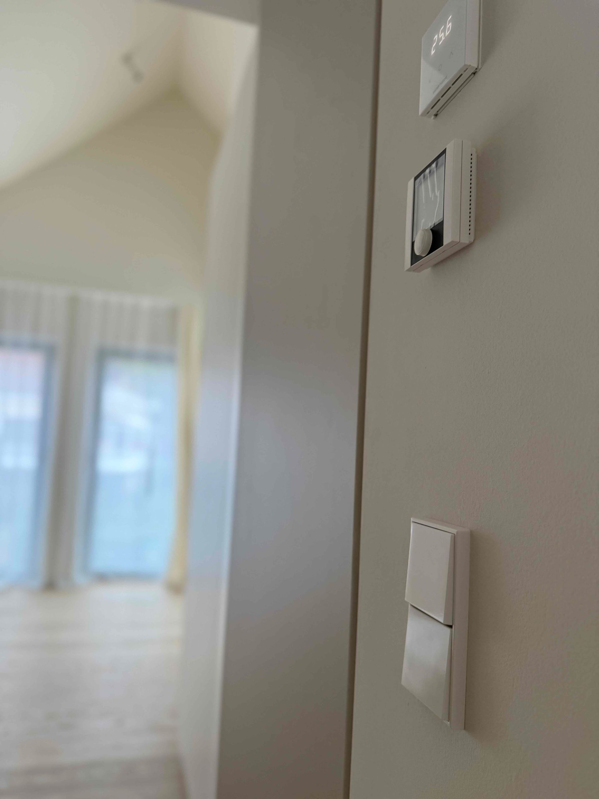 Heller Flur mit weißen Wänden, Fensterlicht und einer Reihe von Lichtschaltern an der rechten Wand