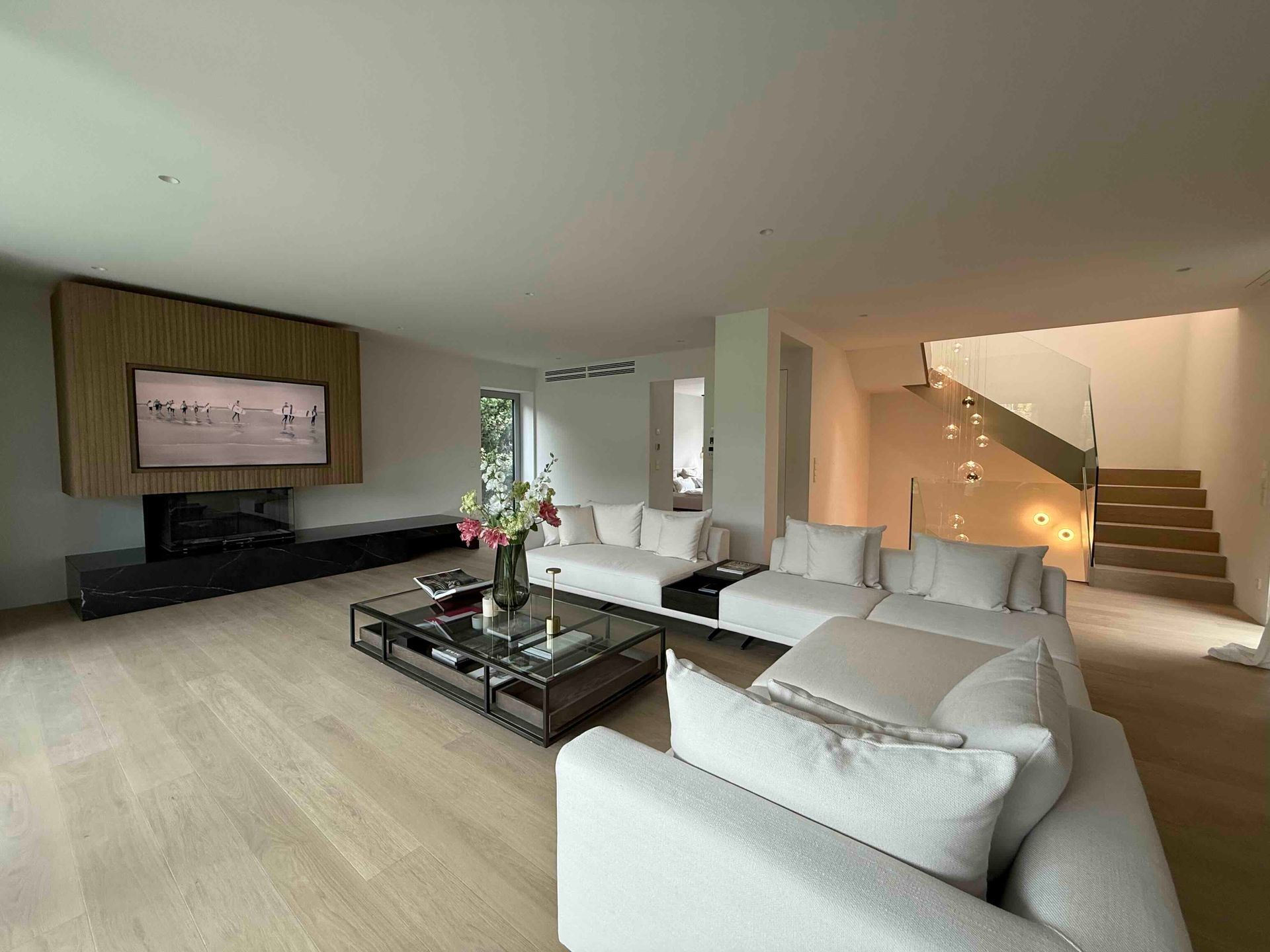 Modernes Wohnzimmer mit weißen Sofas, Couchtisch, Kamin und Treppe