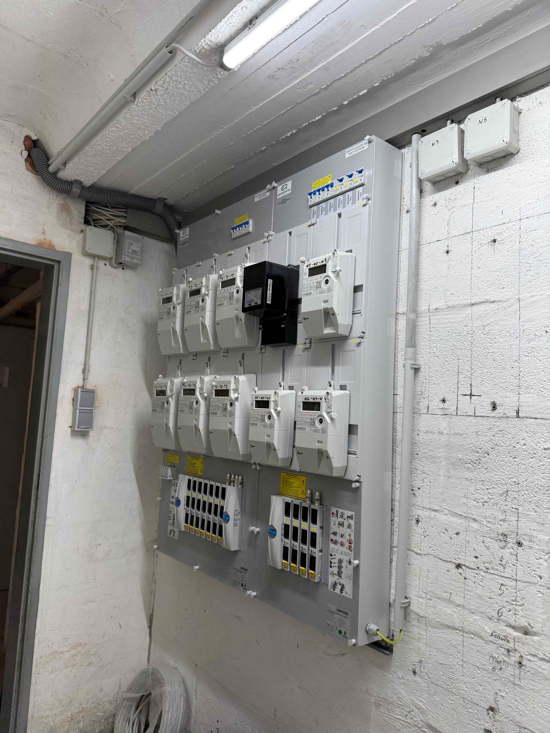 Elektrischer Sicherungskasten in einem Hauswirtschaftsraum mit mehreren Schaltern und Verkabelung an einer weißen Wand