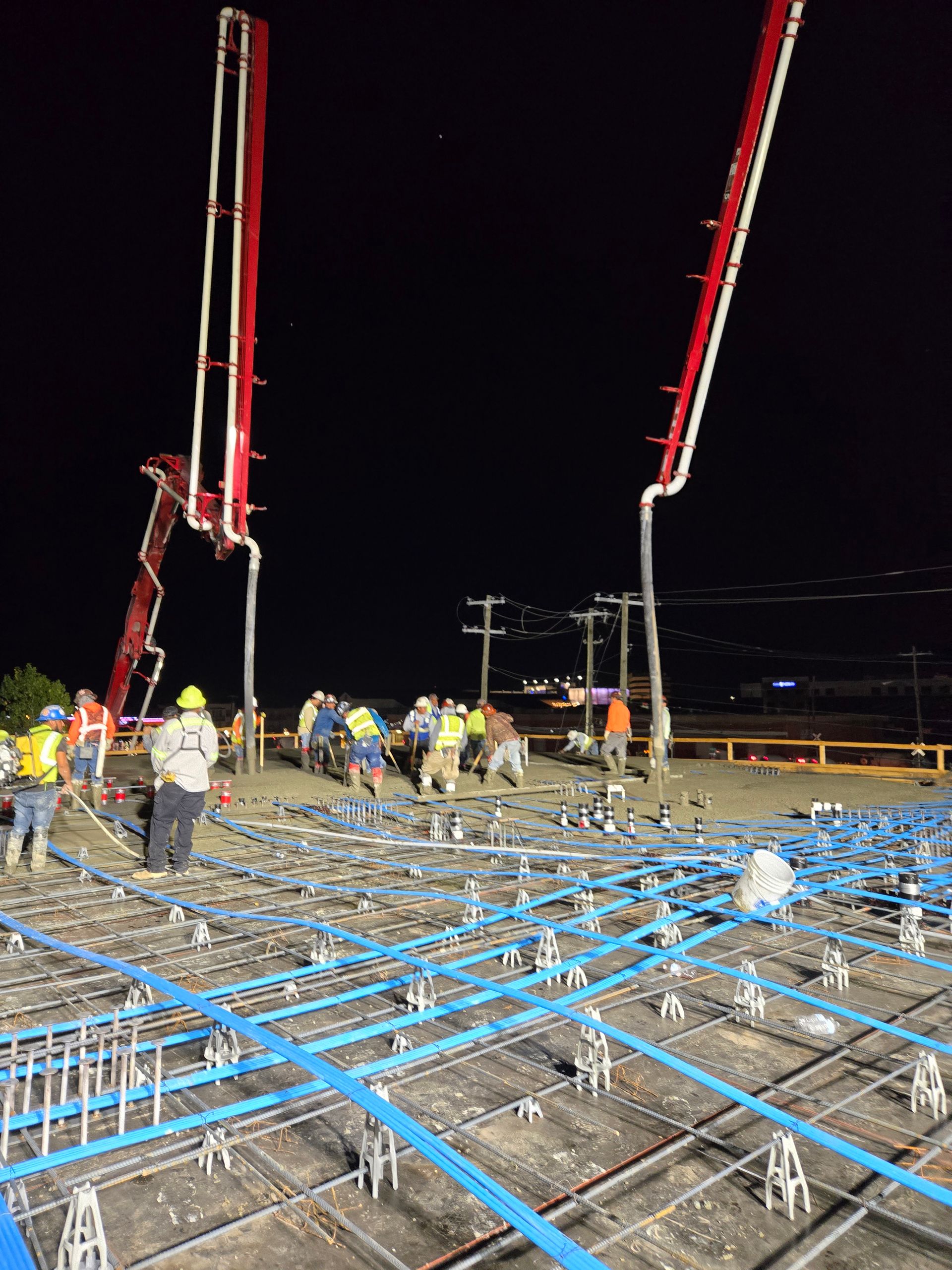 A group of construction workers are working on a concrete floor at night.