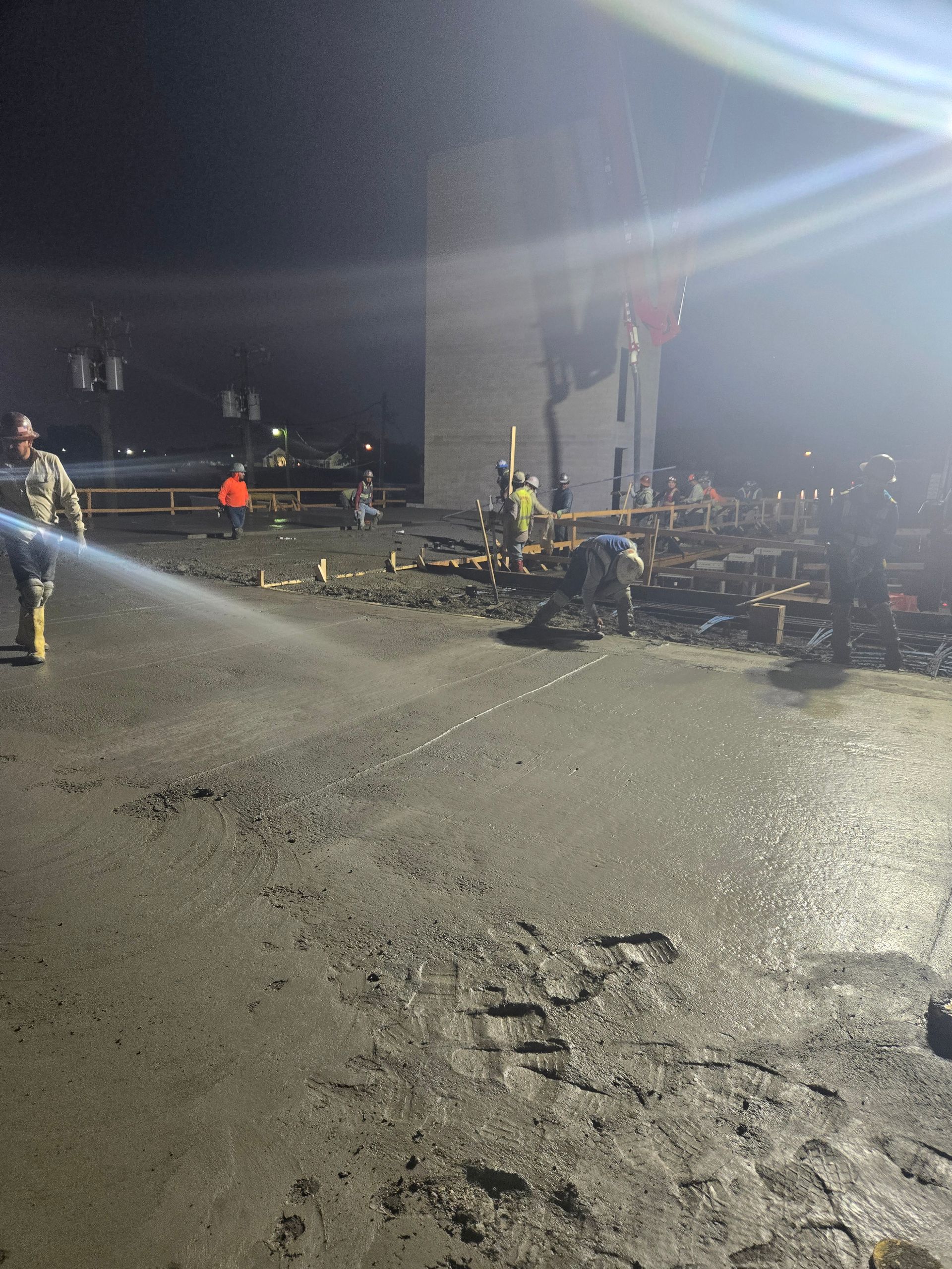 A man is spraying water on the ground at night