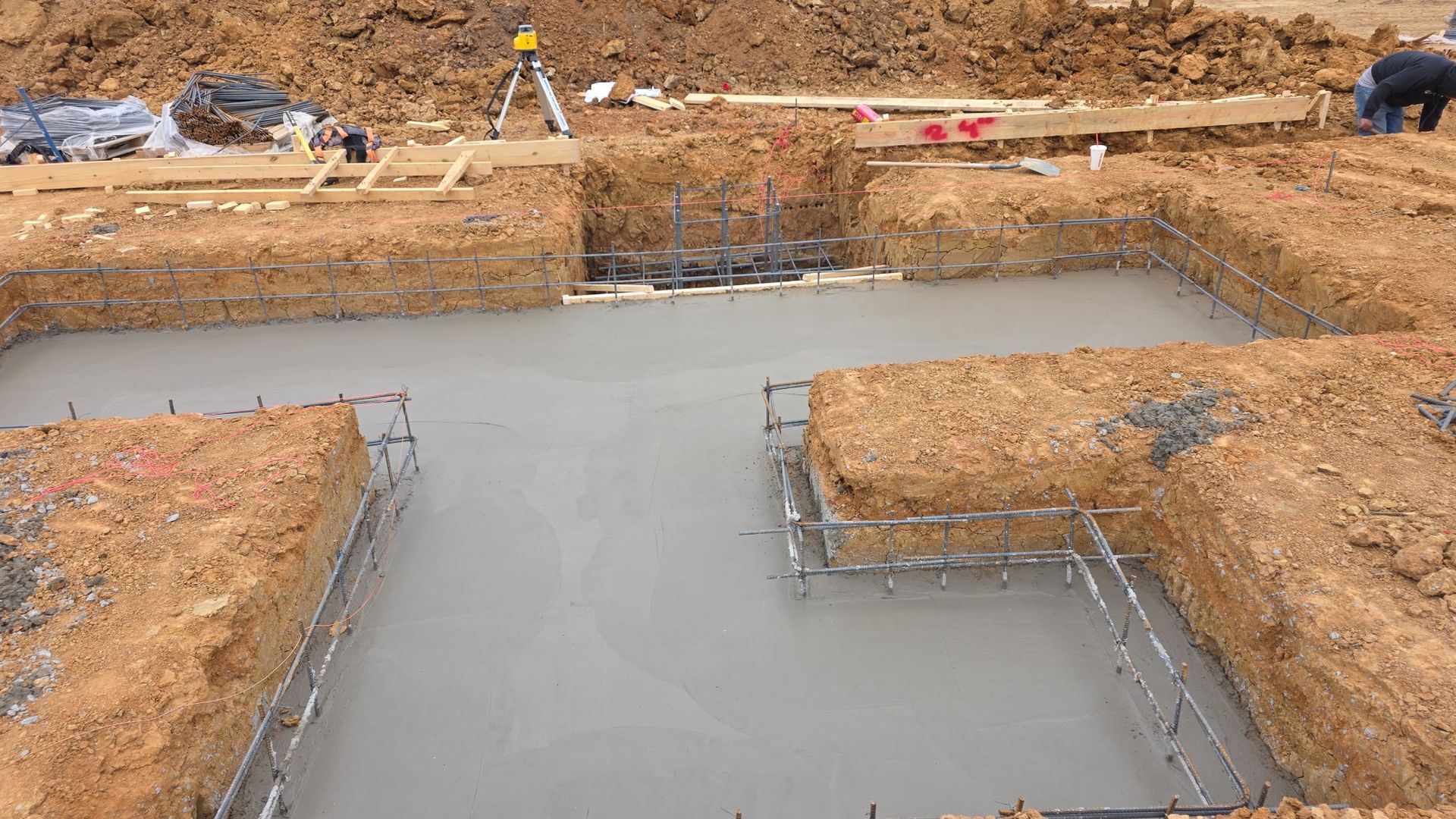 Fresh concrete foundation in an excavated construction site with rebar forms and dirt edges