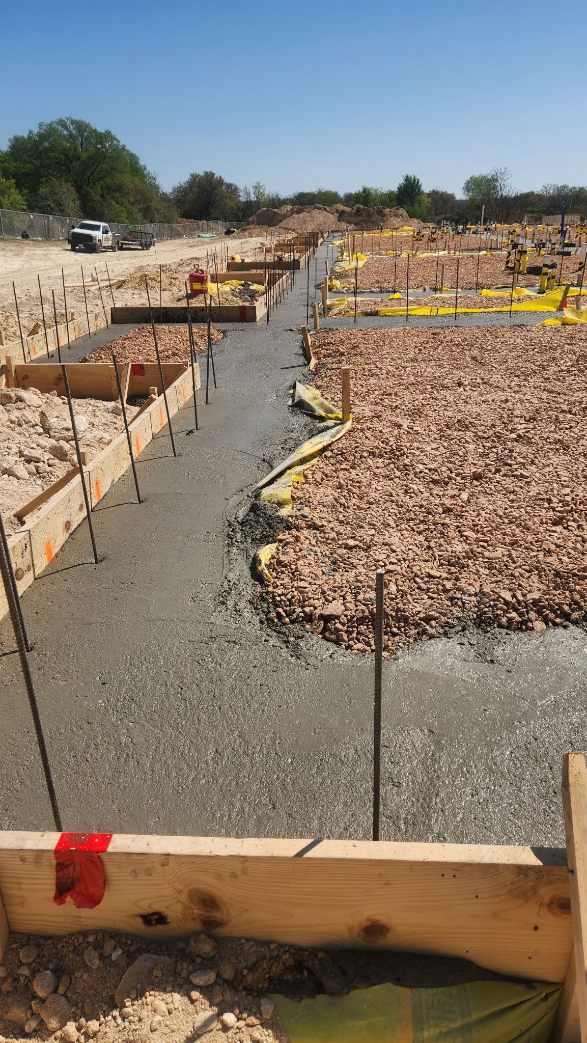 Construction site with gravel foundation trenches and wooden forms under a clear blue sky