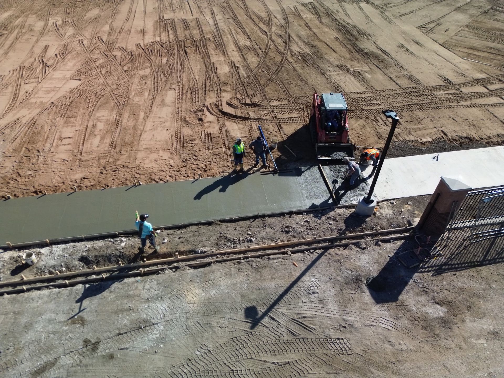 Construction workers pouring concrete along a road beside a truck and paving machine