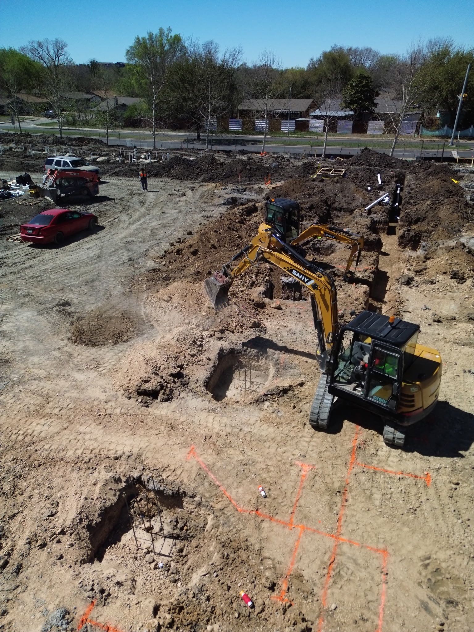 Excavator digging a large dirt trench at a construction site under clear skies