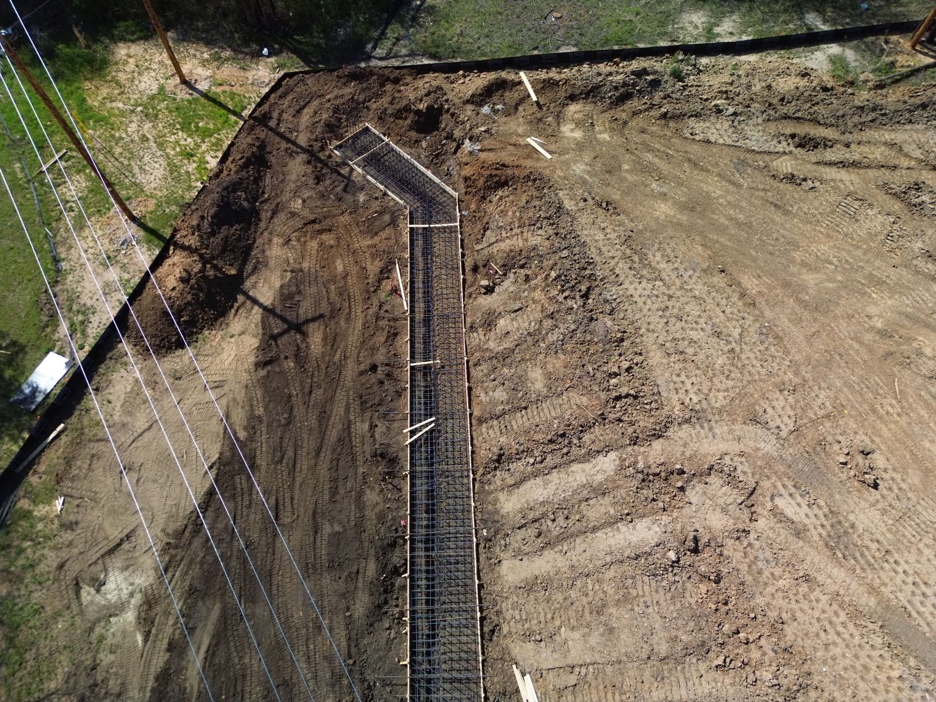 Steep dirt slope with a wire-mesh retaining wall and concrete drainage channel along the edge