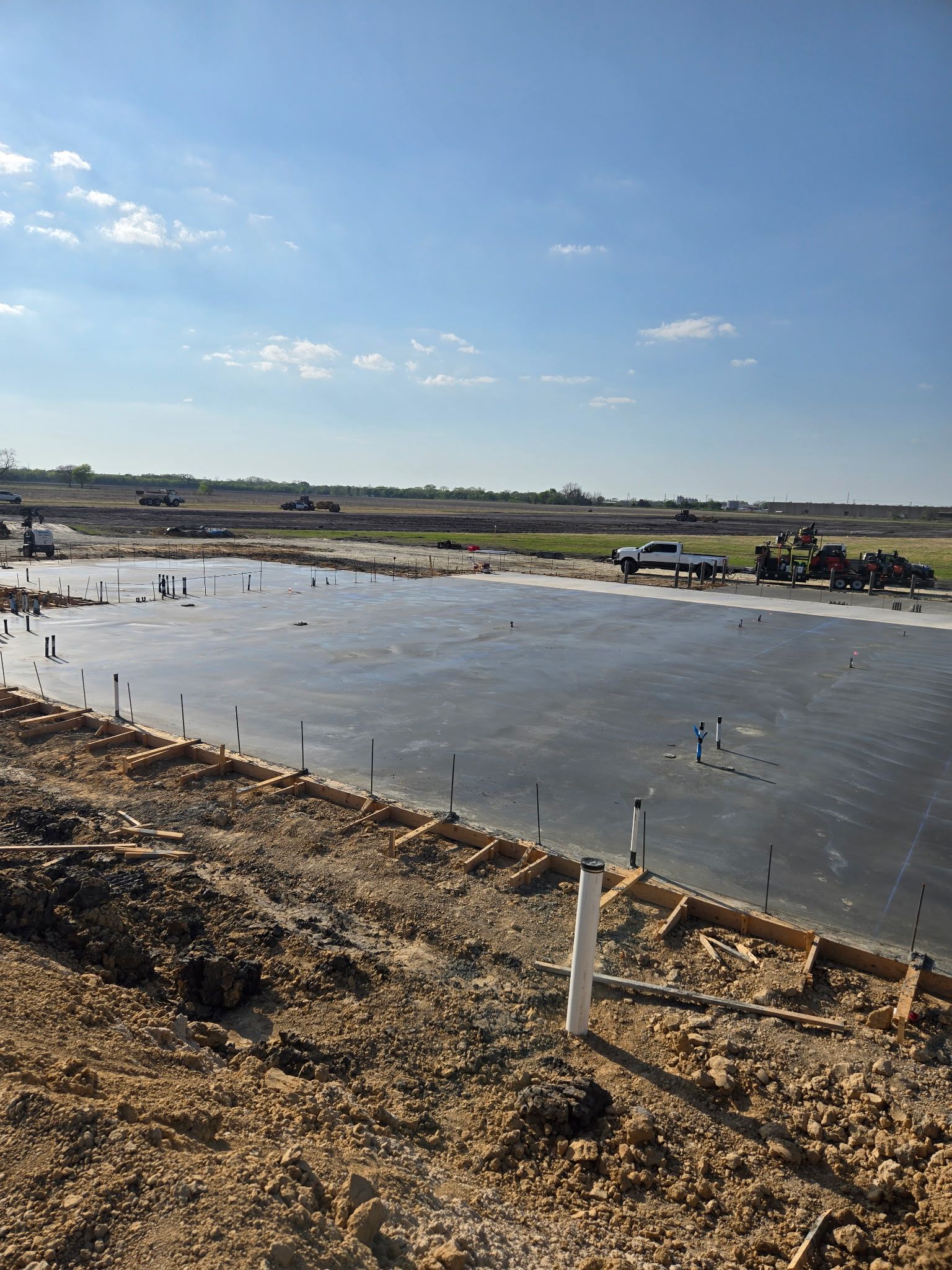 Shallow flooded field with small workers under a bright blue sky, viewed from a dirt embankment