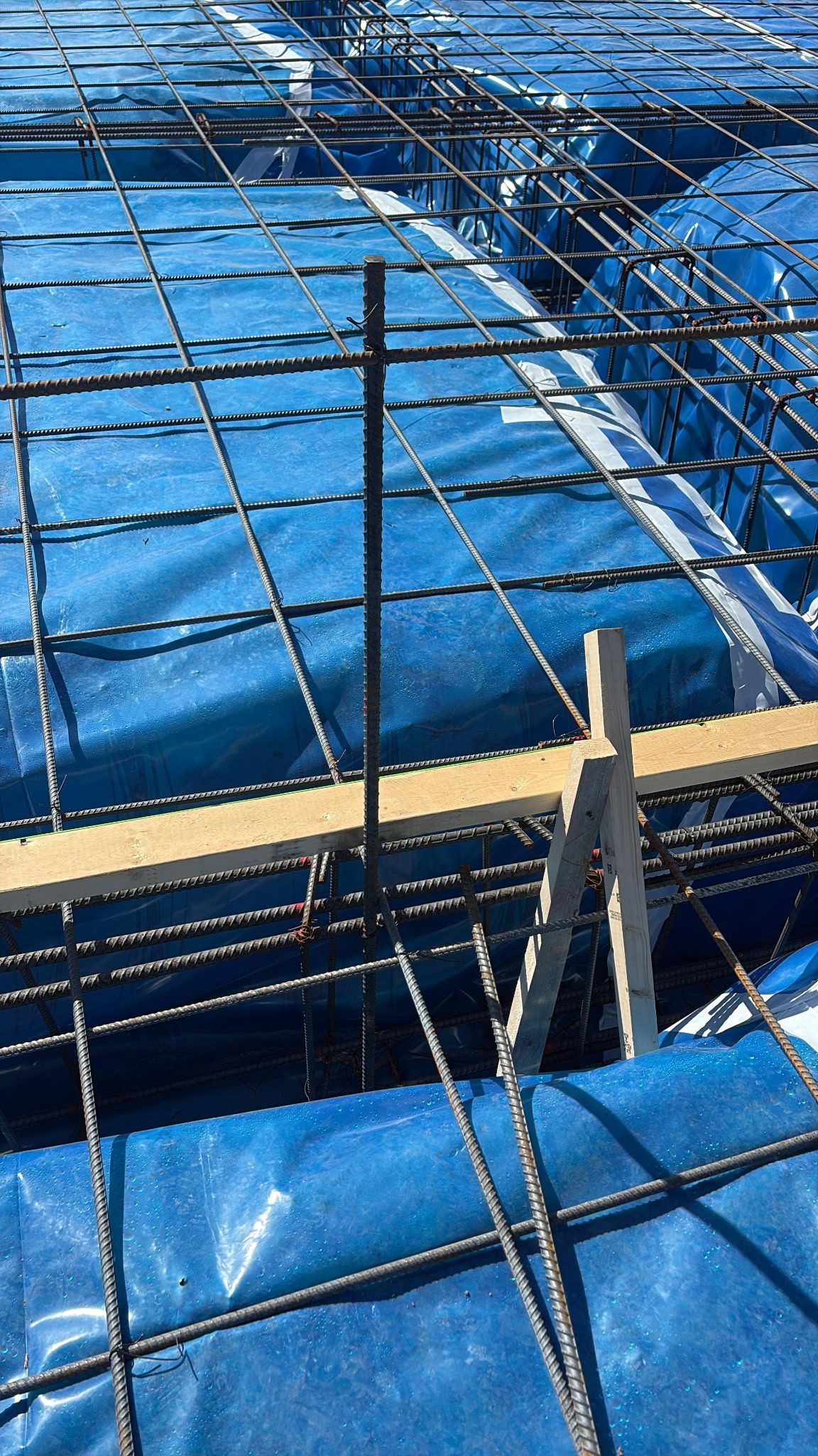 Blue tarp covering a scaffolded construction site with wooden planks and metal supports