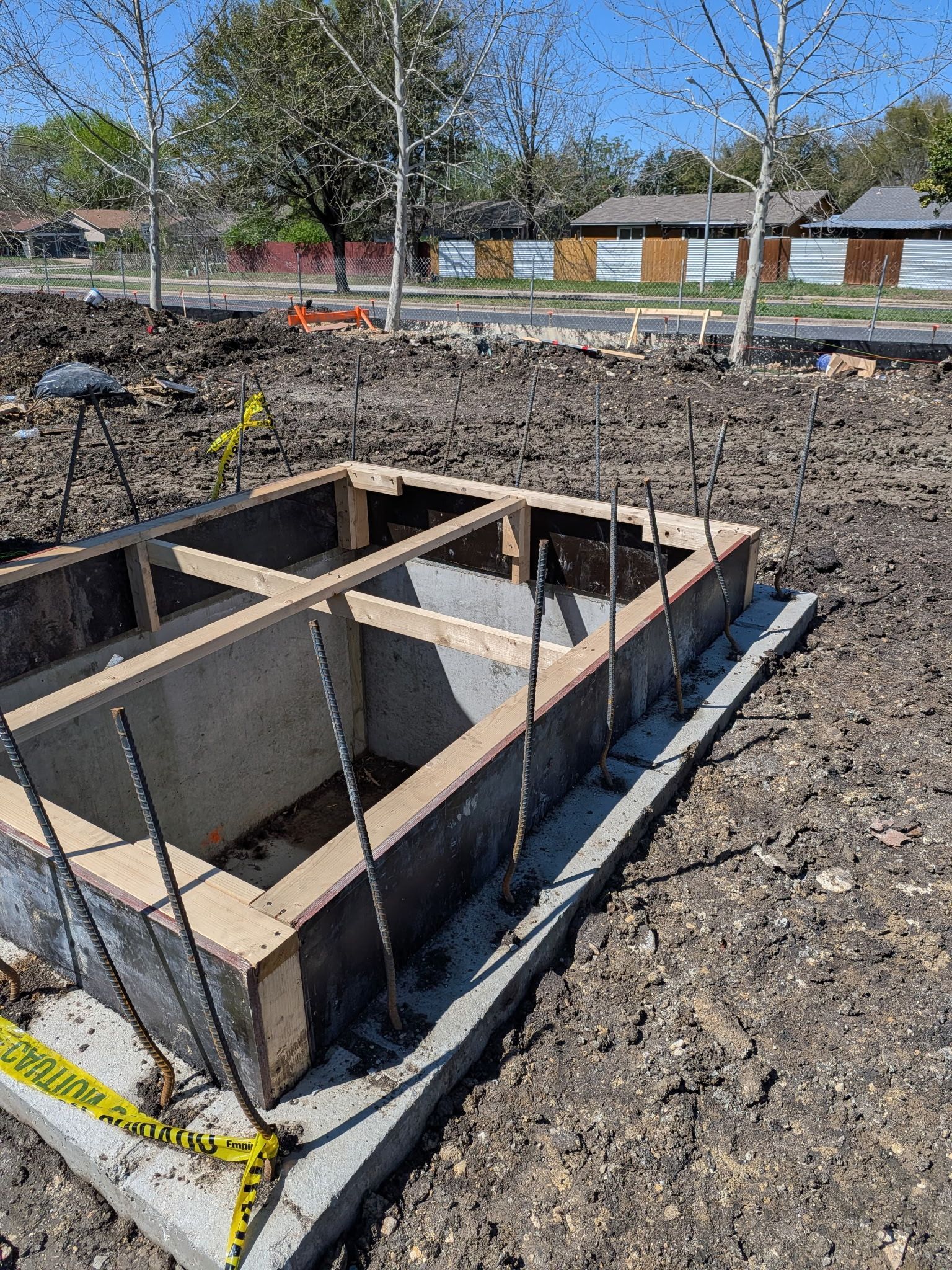 Concrete foundation trench with rebar and wooden forms at a construction site.