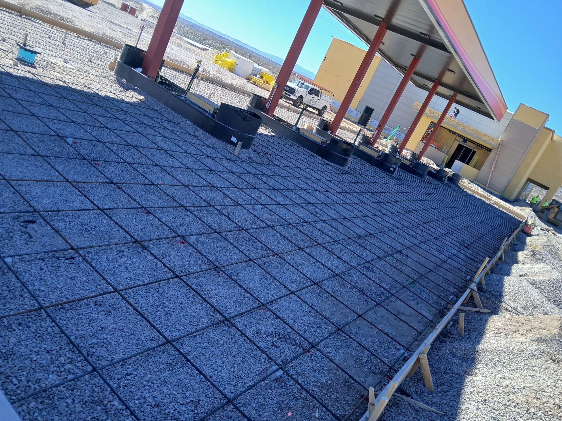 Blue gravel roof under construction beside a building with red beams and beige walls