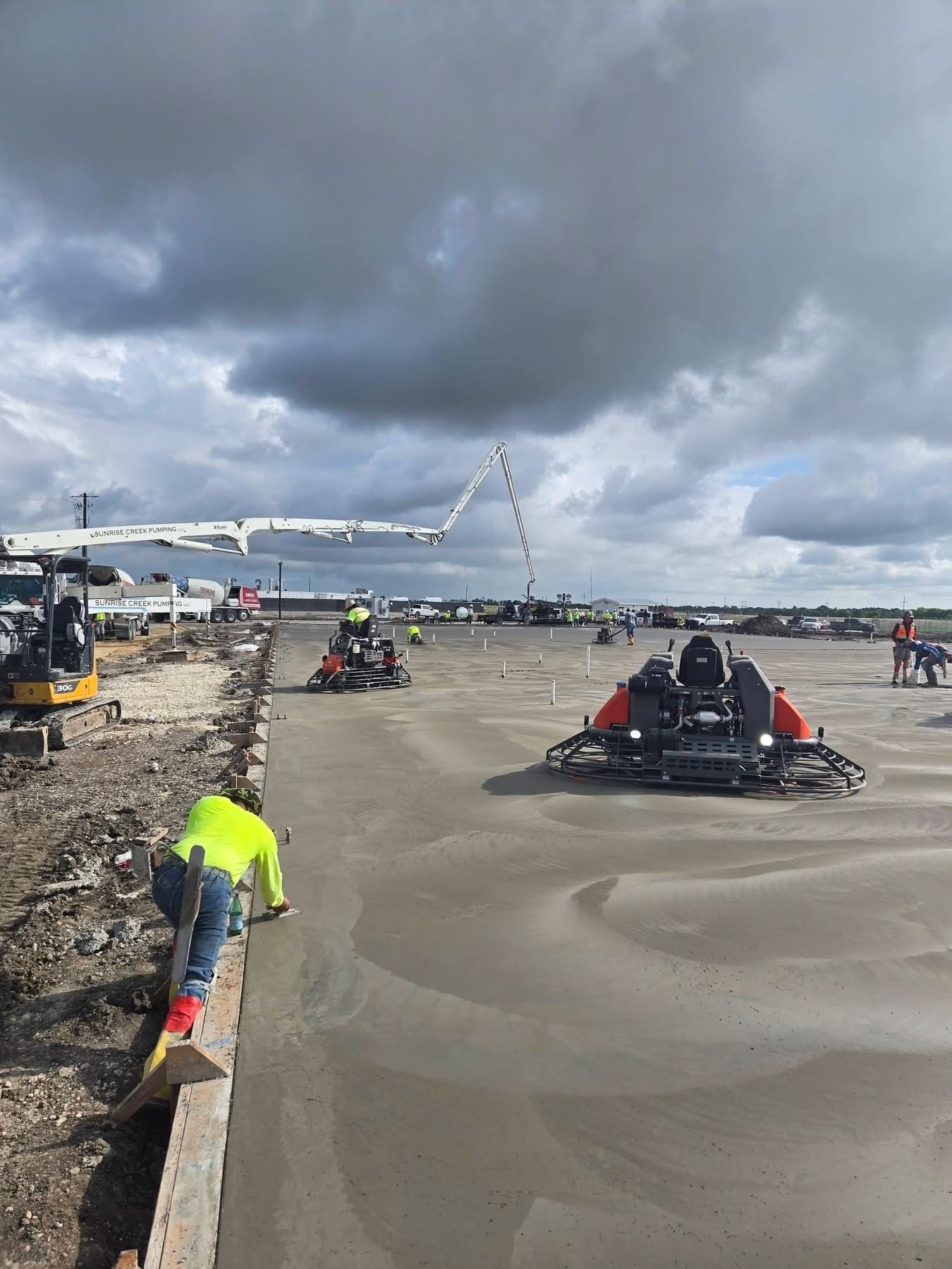 ATVs racing on a muddy beach under cloudy skies, with spectators along the shore