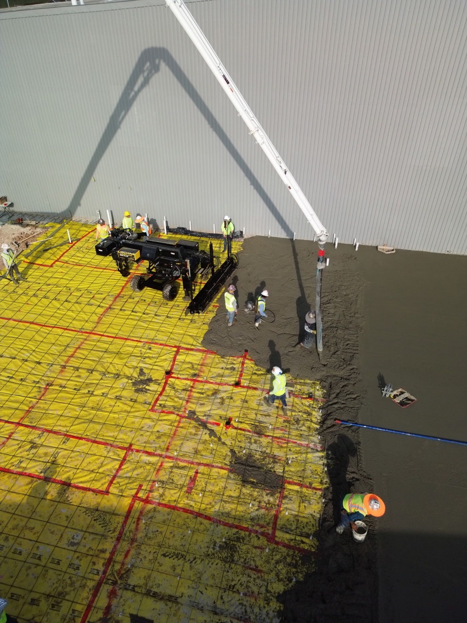 Crowded waterfront dock with yellow netting, a crane, and several people standing near the edge