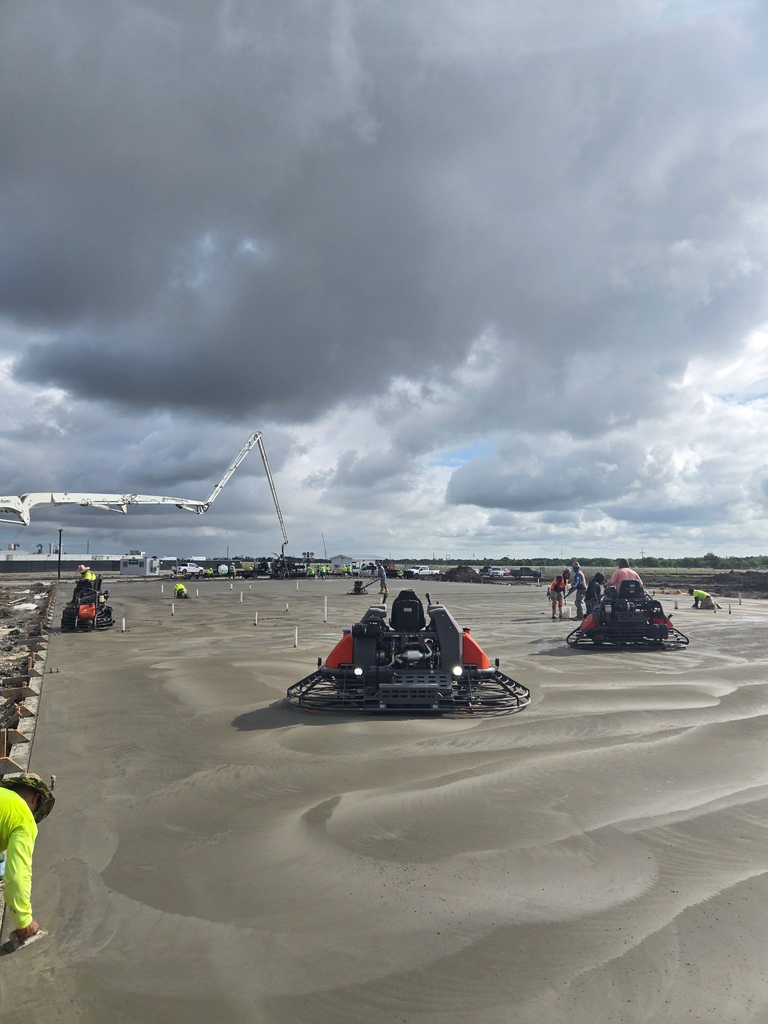 Go-karts racing on a sandy beach under dark cloudy skies, with spectators and a lit arch in the background