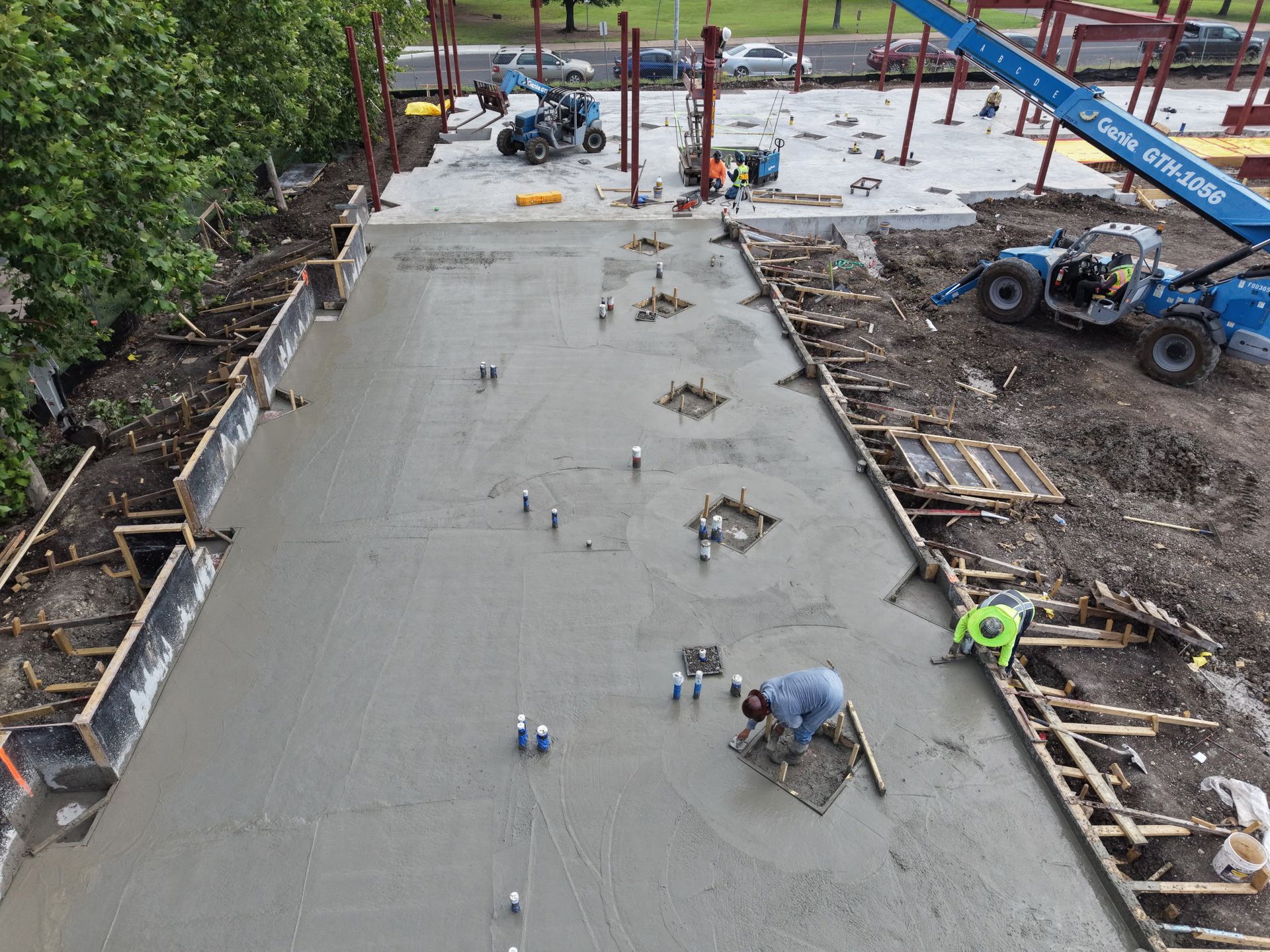 Concrete being poured for a large foundation slab at a construction site, with workers and equipment around it