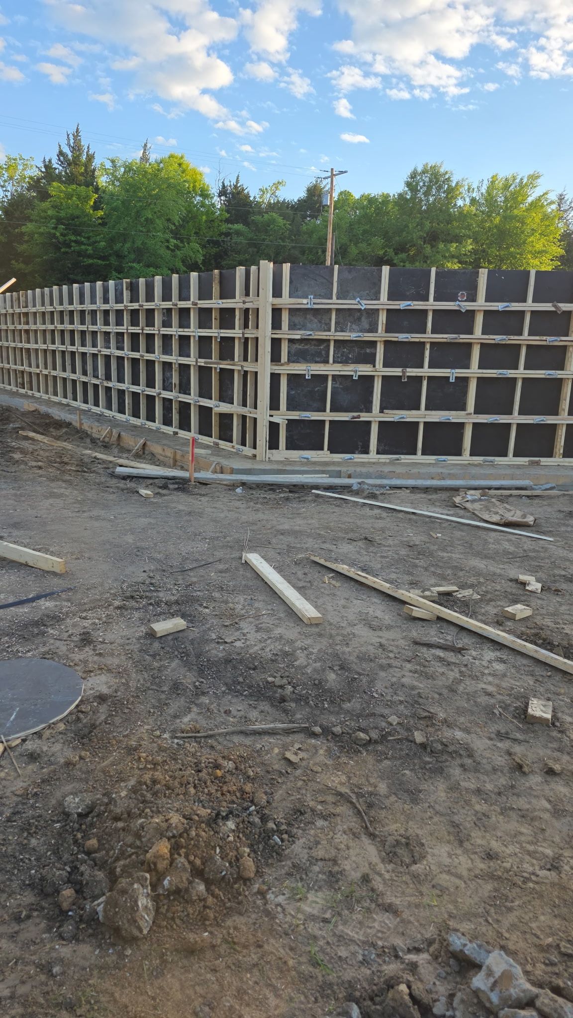 Partially built concrete block wall with wooden formwork at a construction site under a blue sky