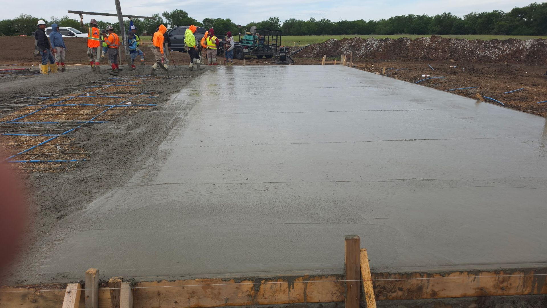 Workers pouring concrete for a roadway foundation at a construction site