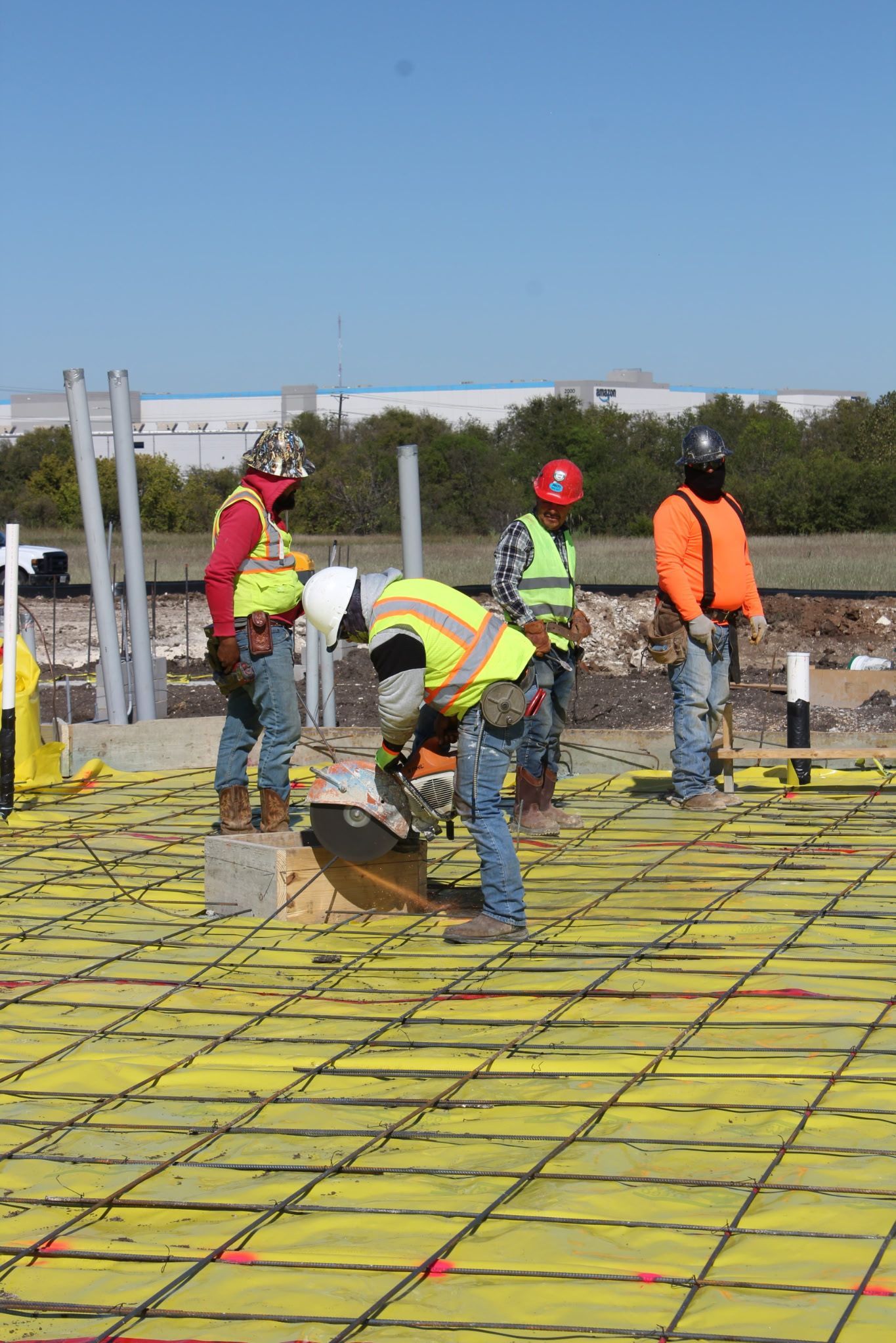 Workers in safety vests and hard hats laying rebar at a construction site