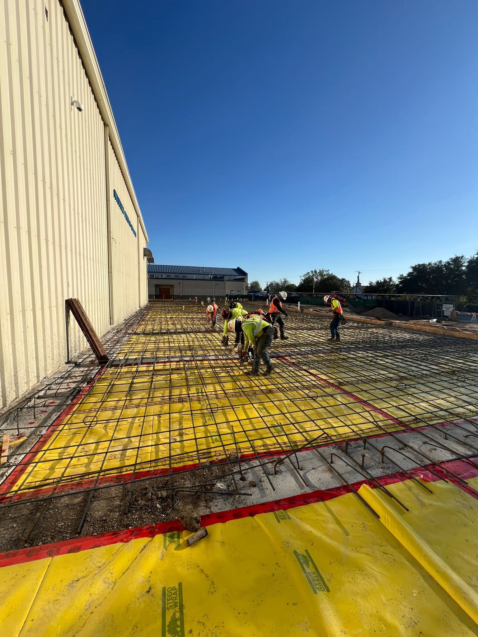 A group of construction workers are working on a concrete floor.
