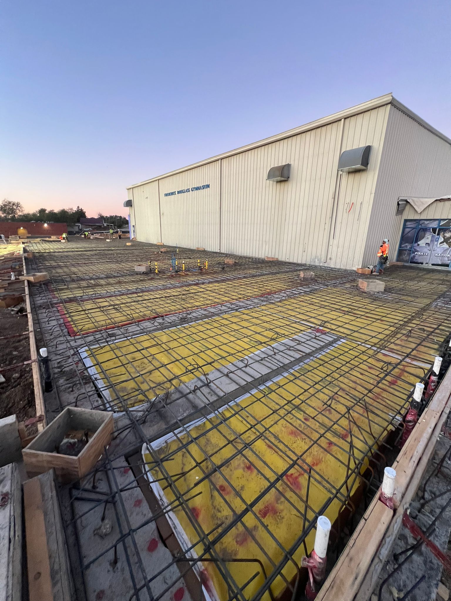 A large building under construction with a lot of concrete in front of it.