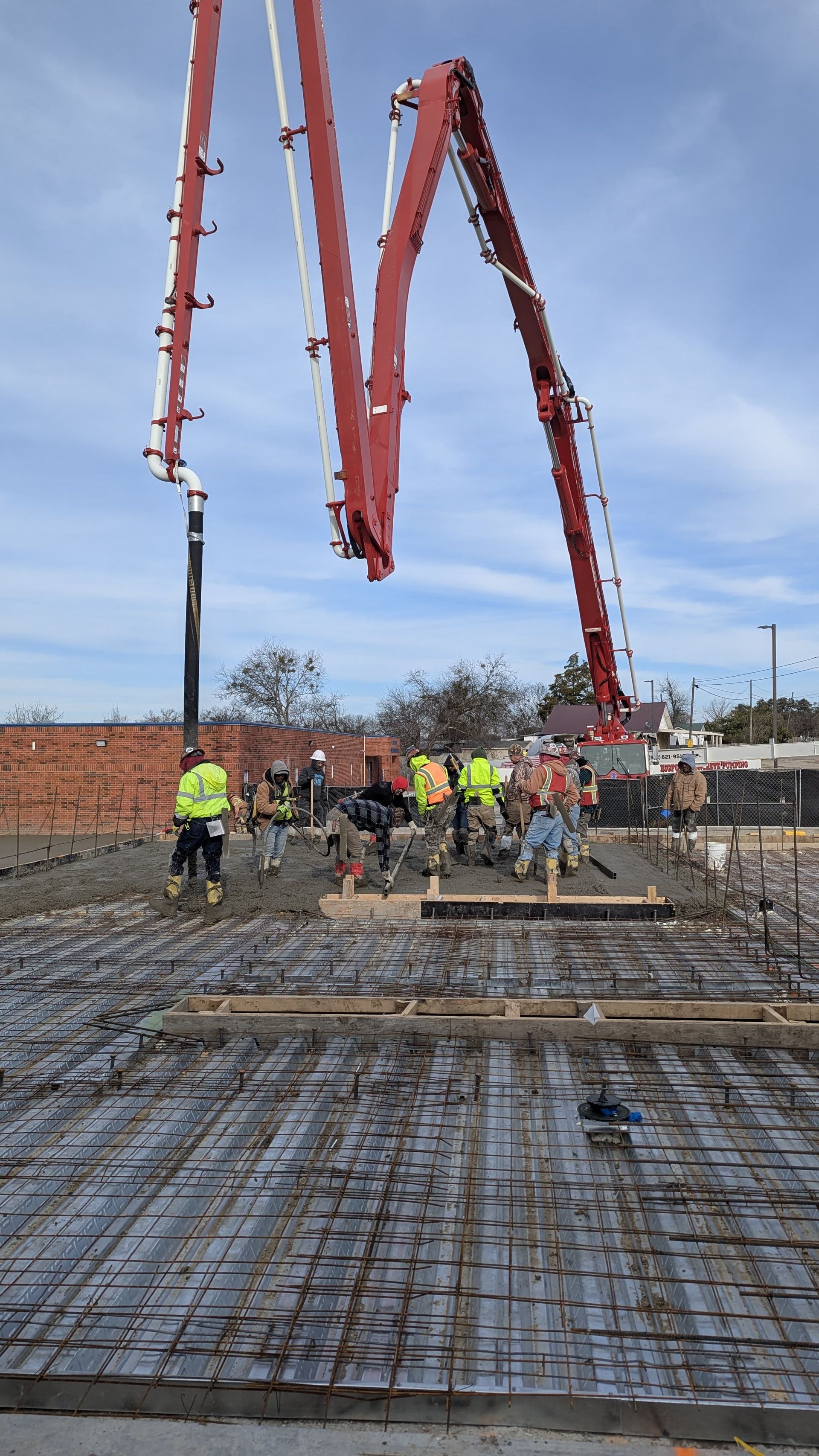 A group of construction workers are standing in front of a concrete pump.