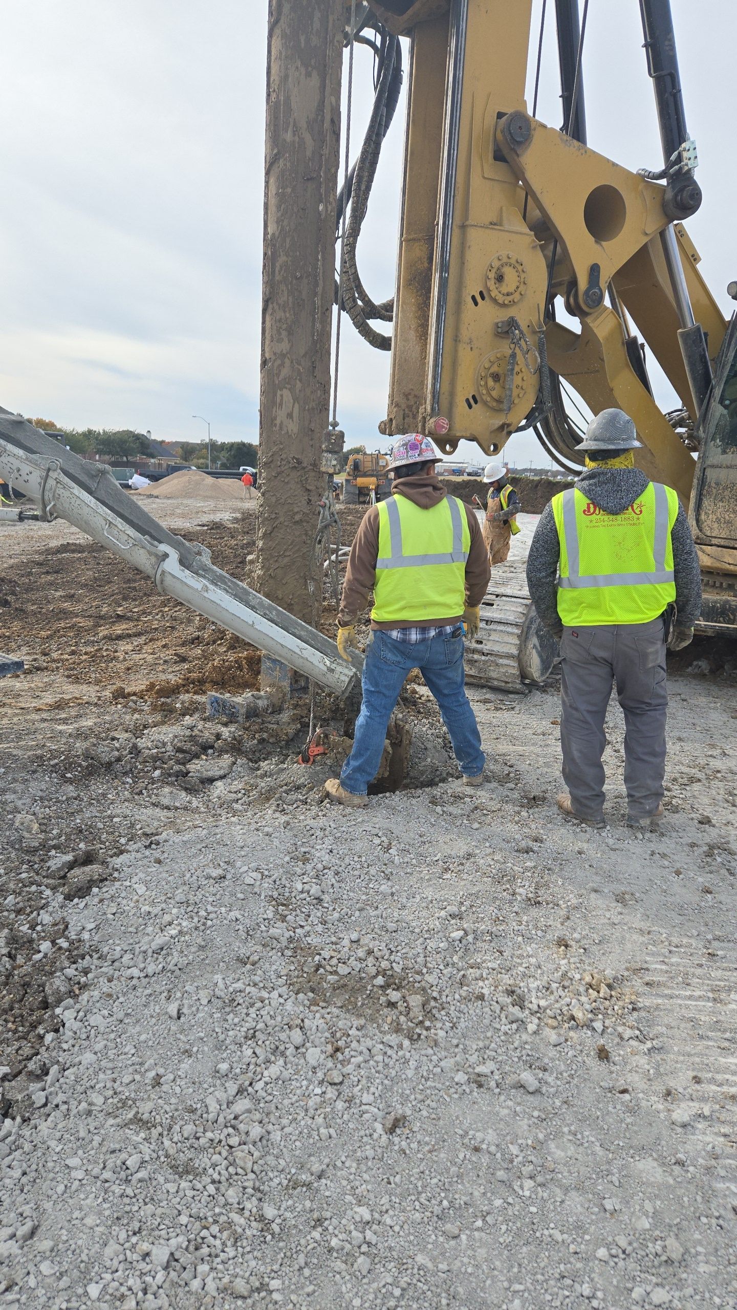 Two construction workers are standing in front of a large machine.