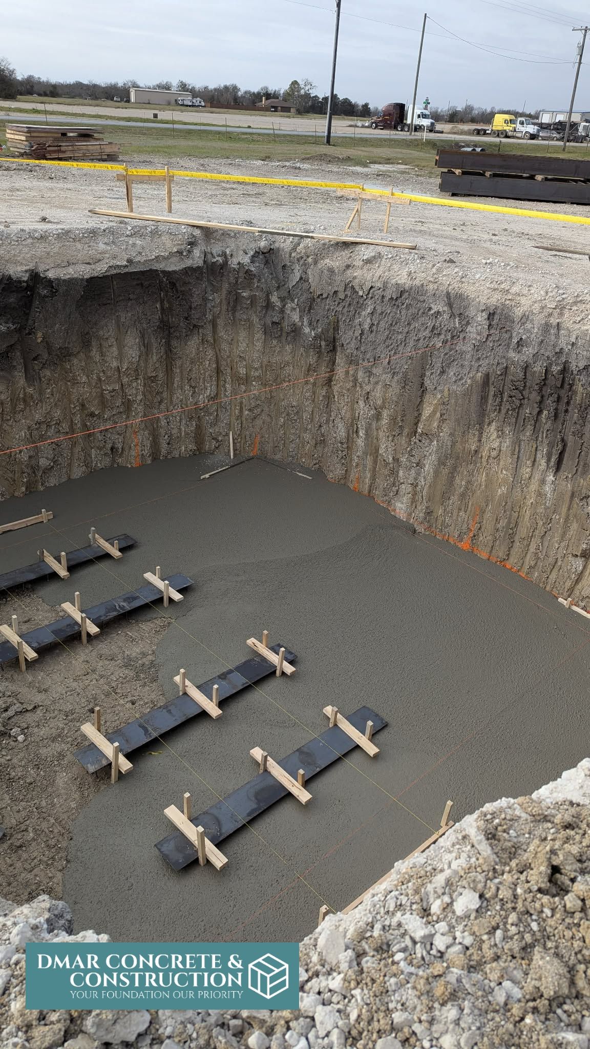 Deep excavation pit lined with concrete forms and gravel at a construction site
