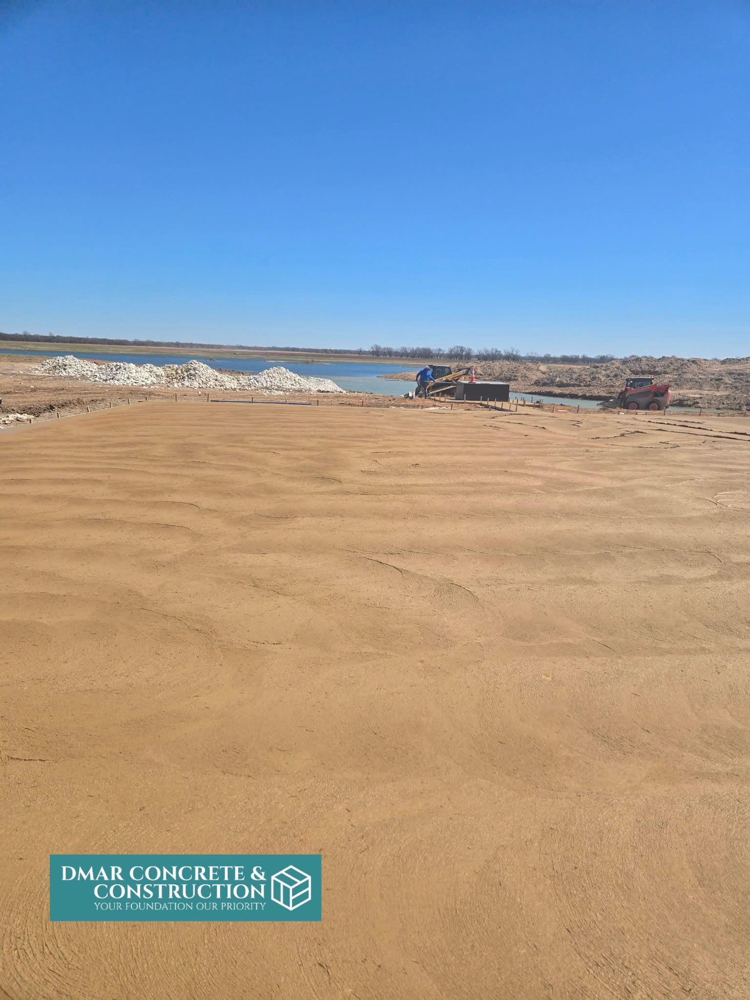 Wide sandy beach under a clear blue sky, with waves and boats near the shoreline.