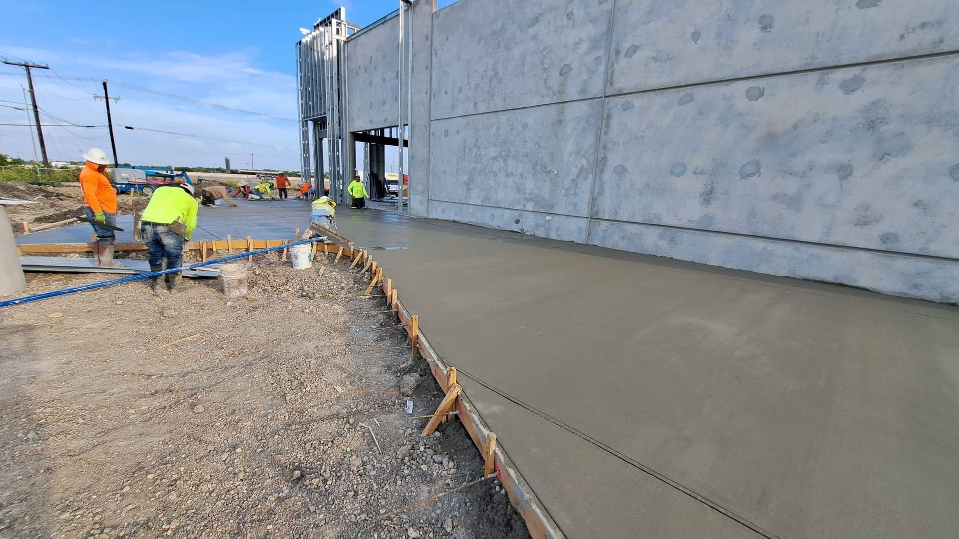 A group of construction workers are working on a sidewalk in front of a building.