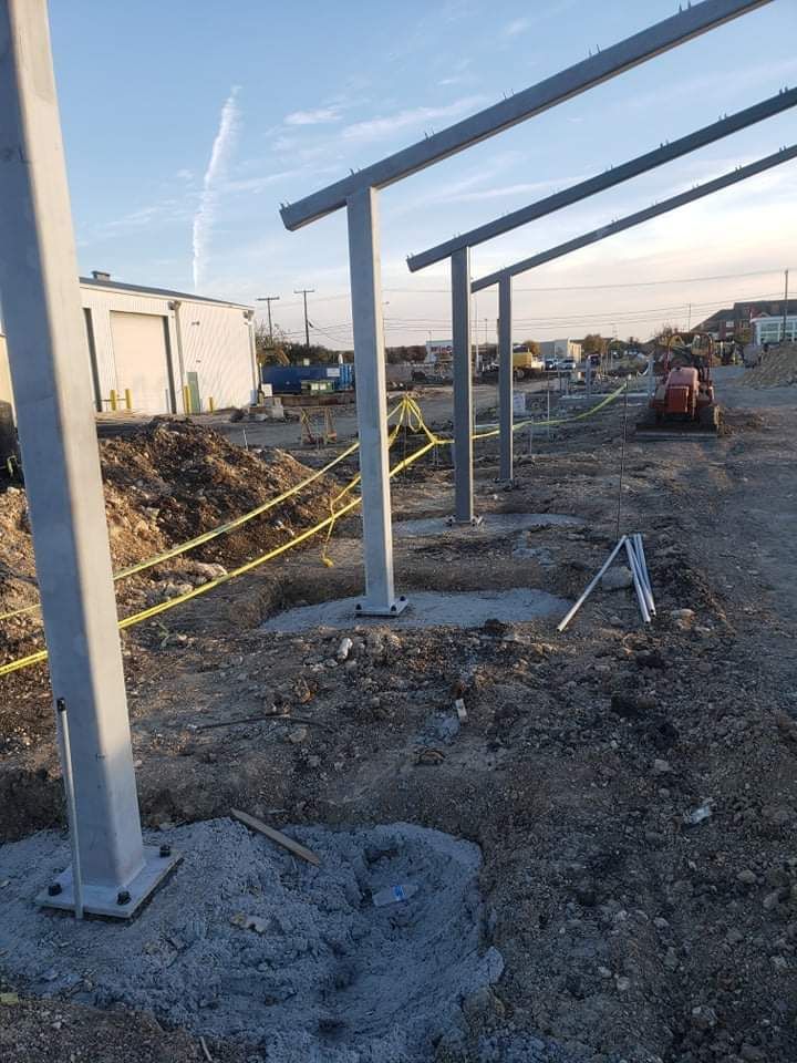 A row of metal poles sitting on top of a dirt field.