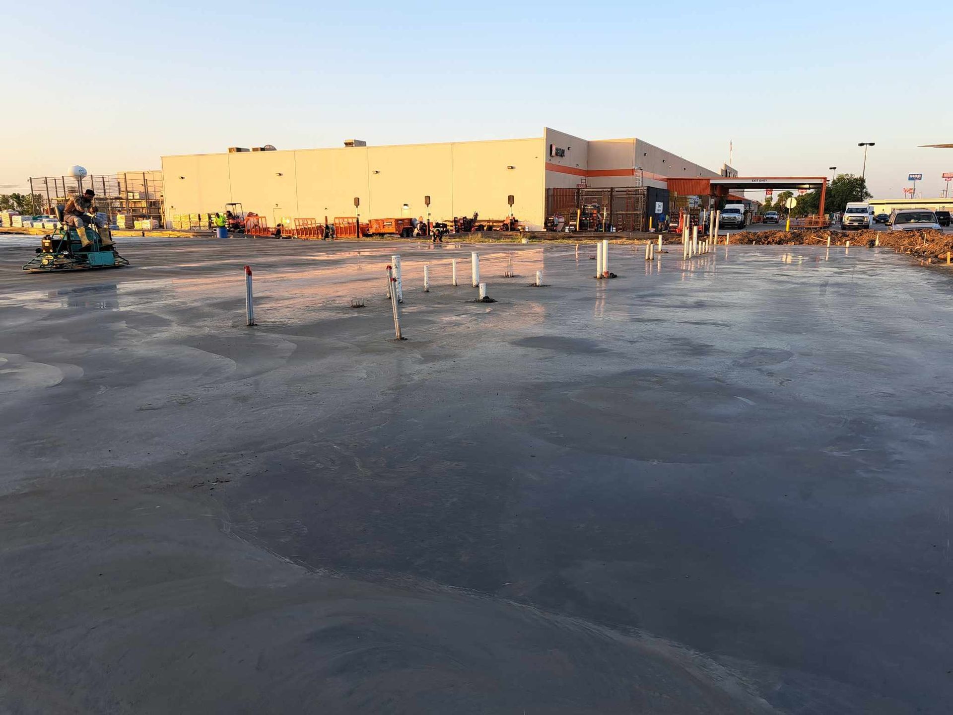 A large concrete parking lot is being built in front of a large building.