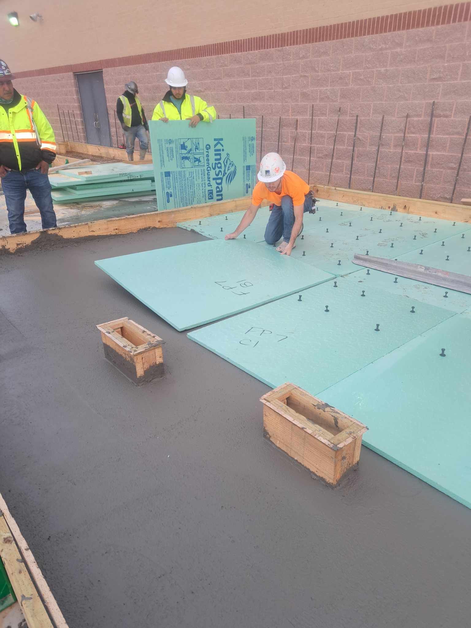 A group of construction workers are working on a concrete floor.