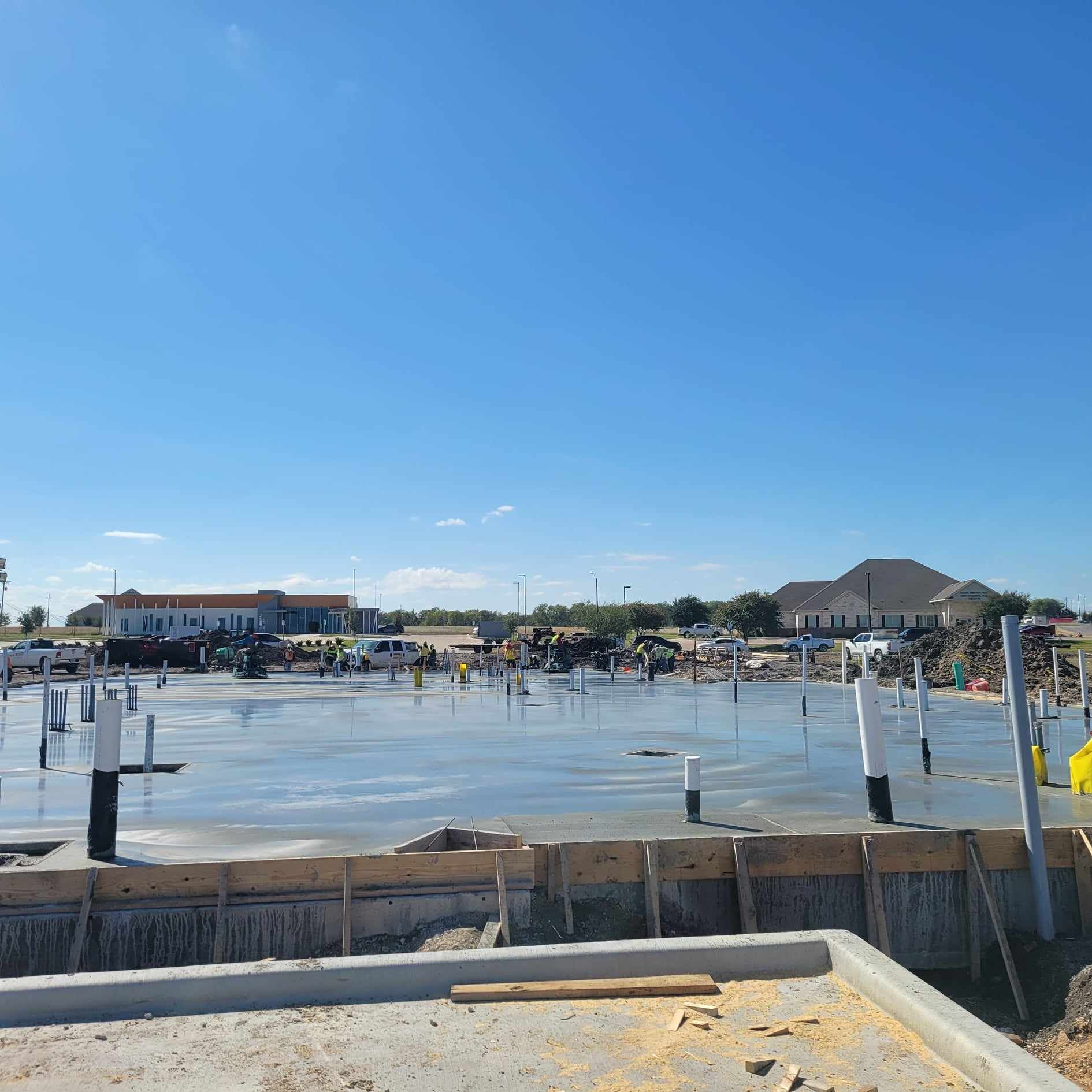 A concrete base for a house is being built on a sunny day.