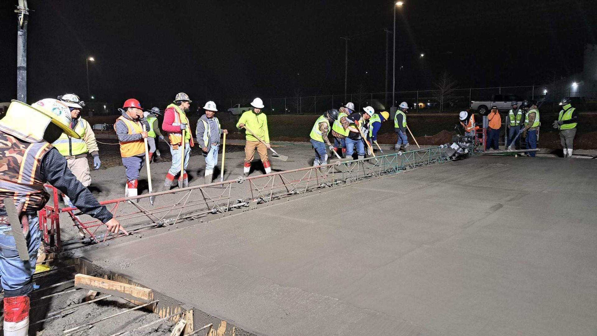A group of construction workers are working on a road at night.