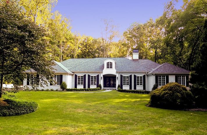 A large white house with a green roof and black shutters