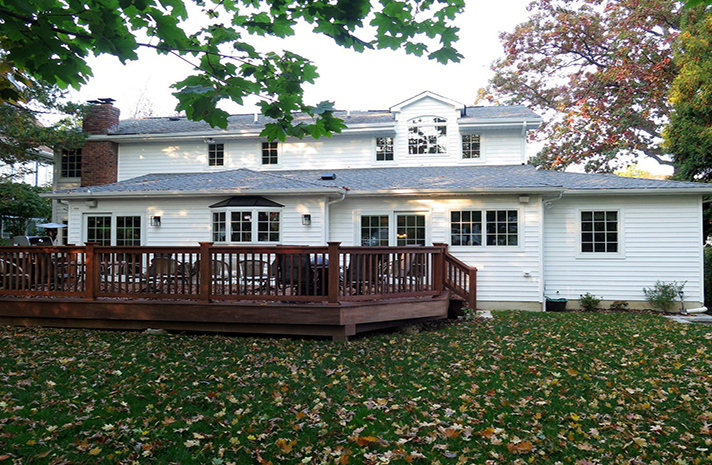 A large white house with a large deck in front of it