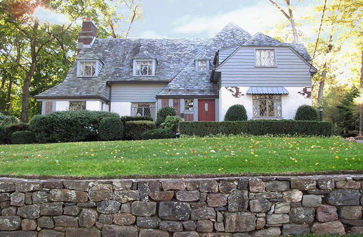 A large house with a stone wall in front of it.