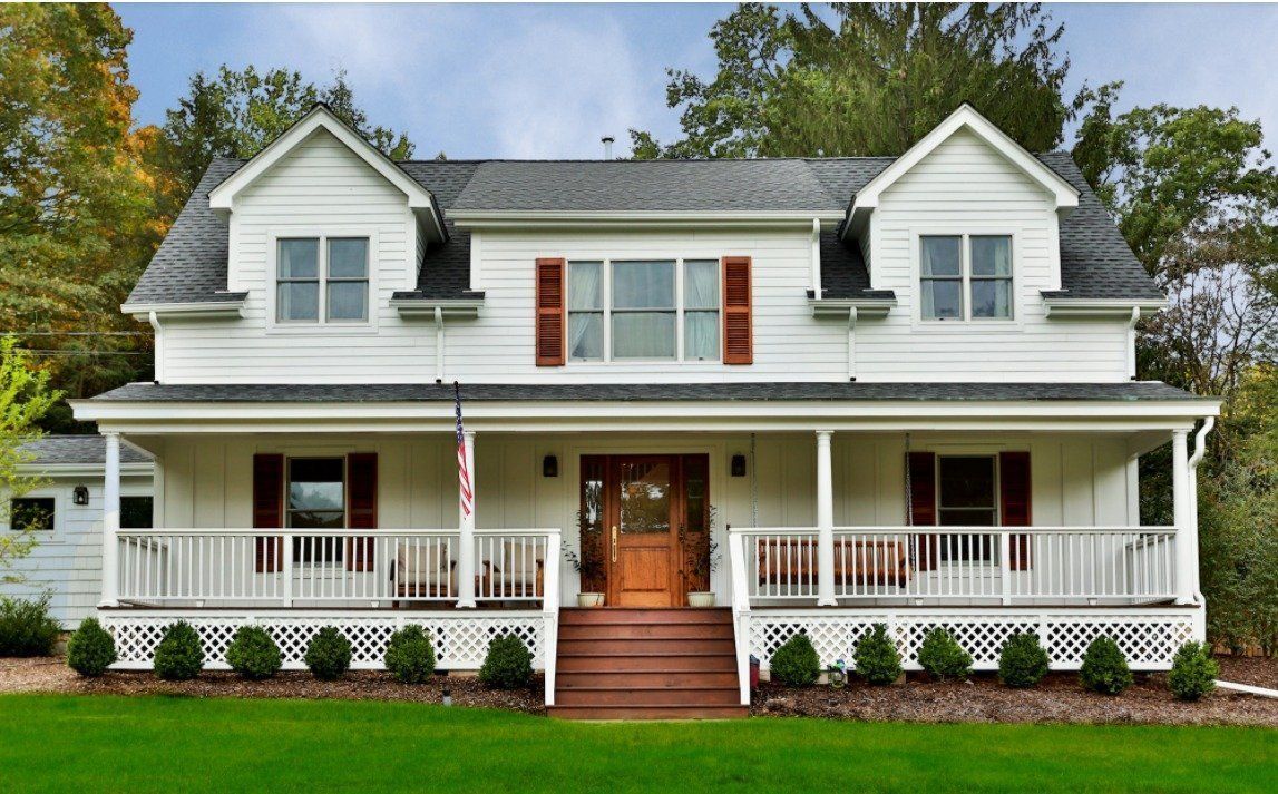 A large white house with a large porch and stairs