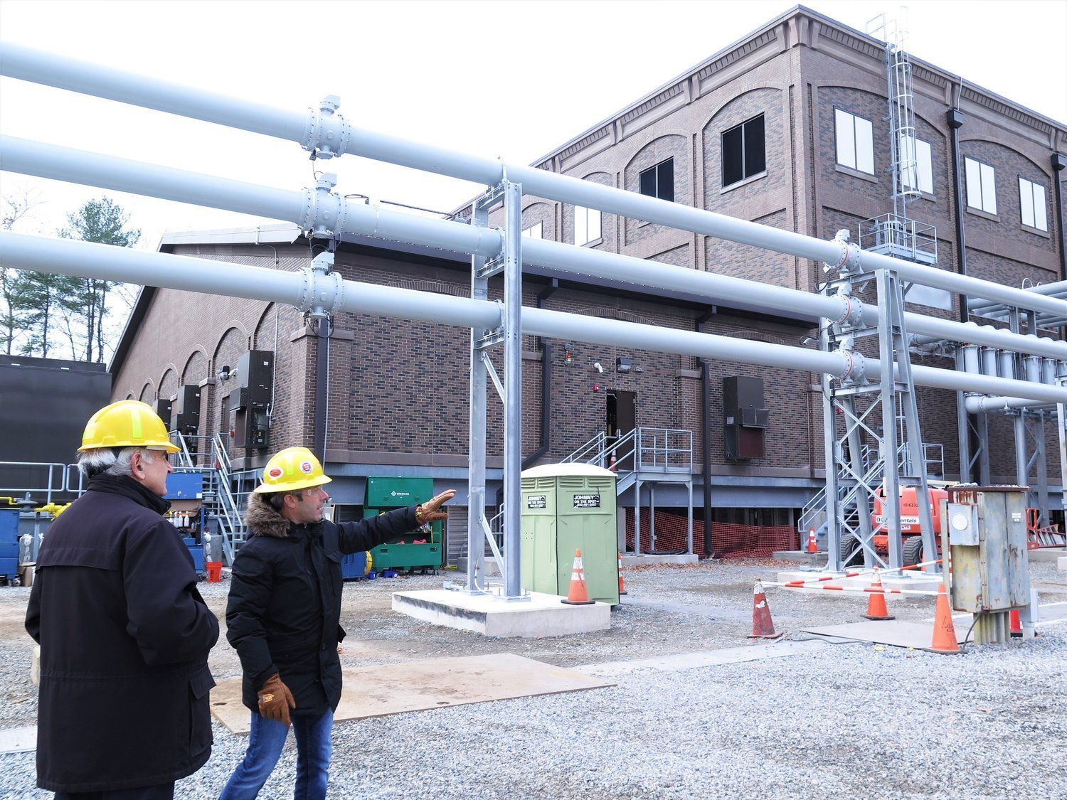 Two men wearing hard hats are standing in front of a building.