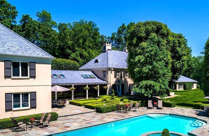 A large house with a large swimming pool in front of it.