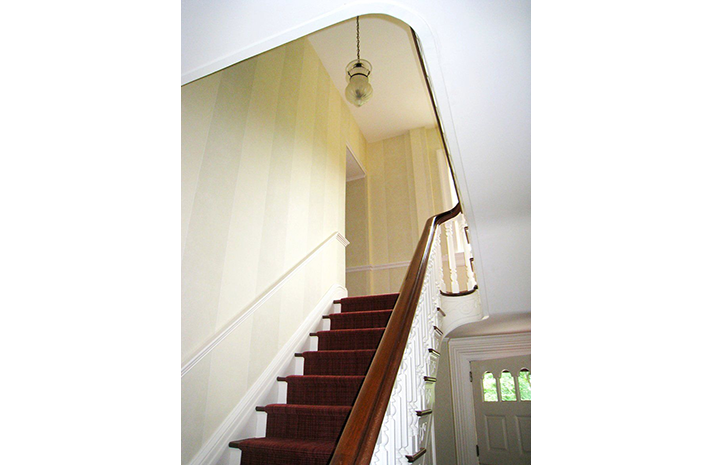 A staircase with a red carpet and a wooden railing