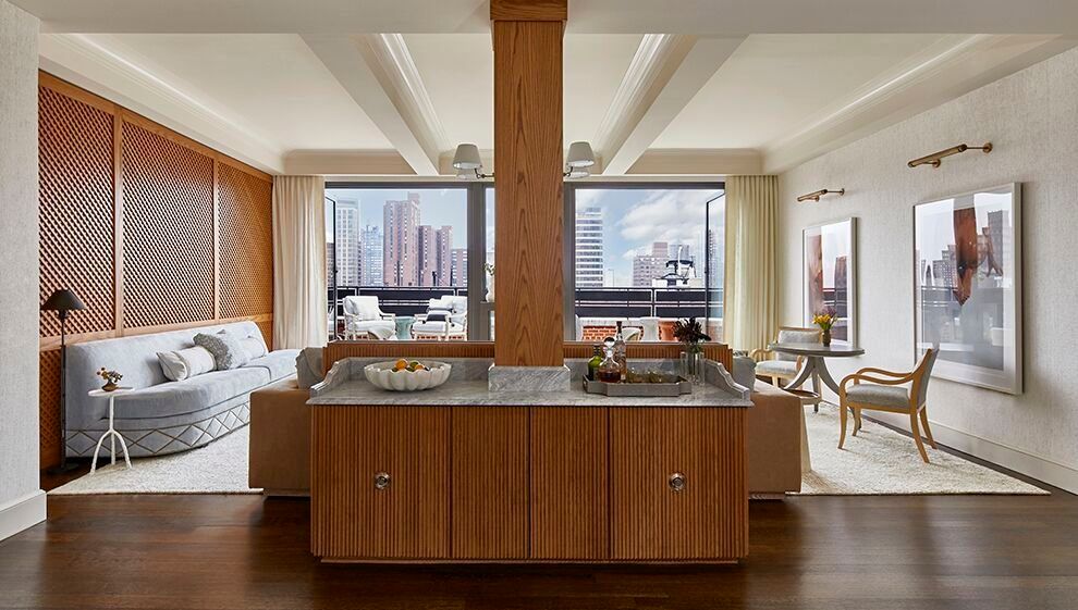 A living room with a couch , chairs , and a kitchen with a wooden island.