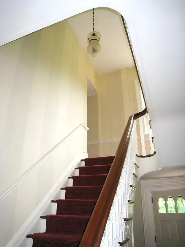 A staircase with a red carpet and white railing