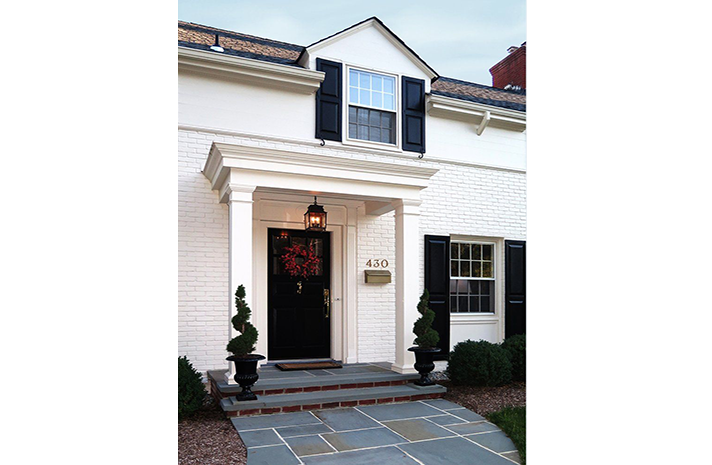 A white house with black shutters and a black door