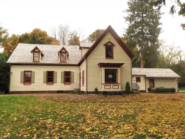 A house with a lot of leaves on the ground in front of it